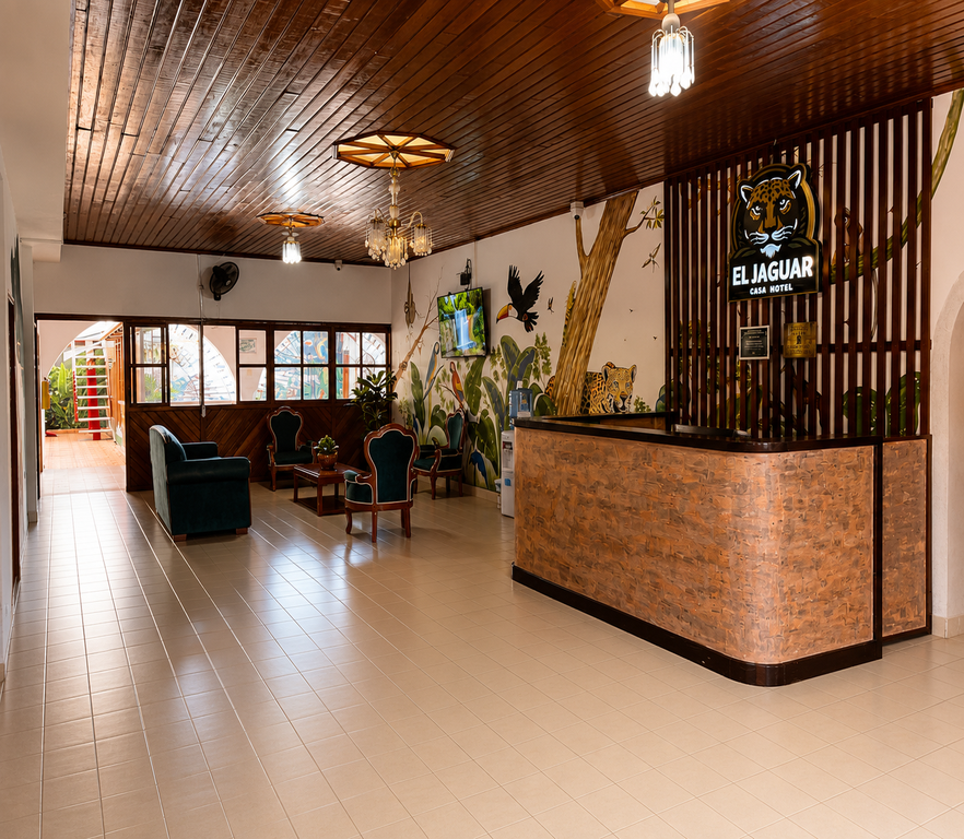 Lobby de El Jaguar Casa Hotel con recepción de madera, mural de selva y techo artesonado
